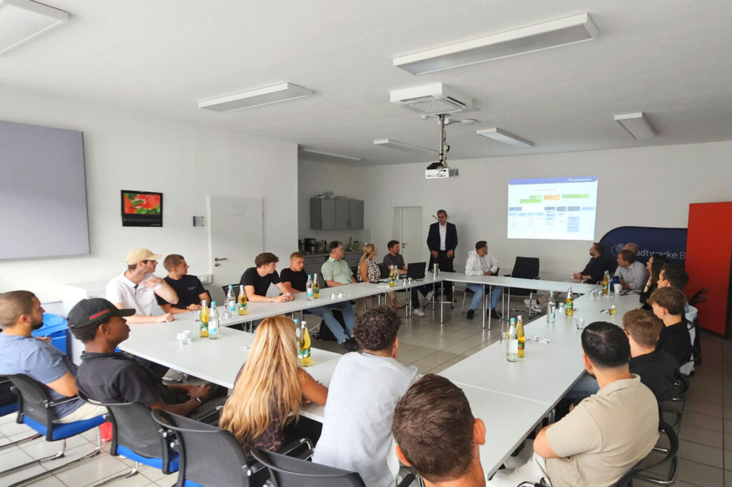 Auszubildende und ihr Ausbilder sitzen zur Begrüßung im Konferenzsaal