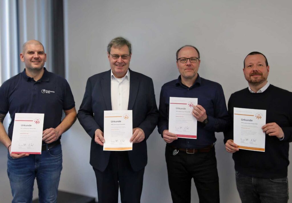 Vier Männer halten jeweils eine Urkunde