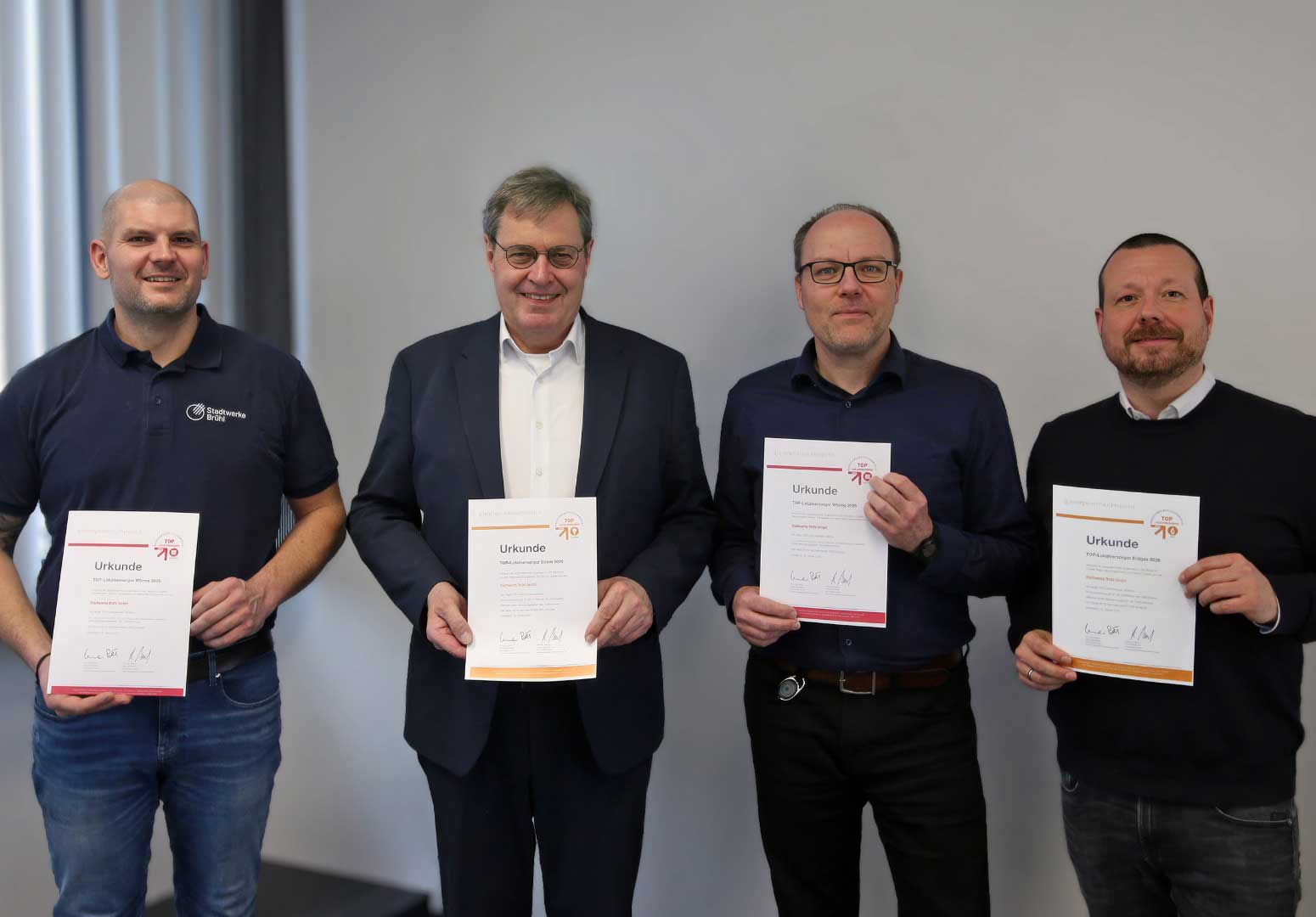 Vier Männer halten jeweils eine Urkunde