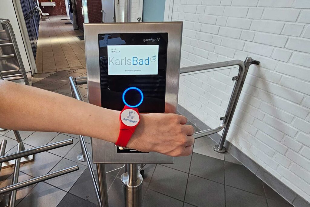 Arm hält rotes Wertband an Automaten am Drehkreuz