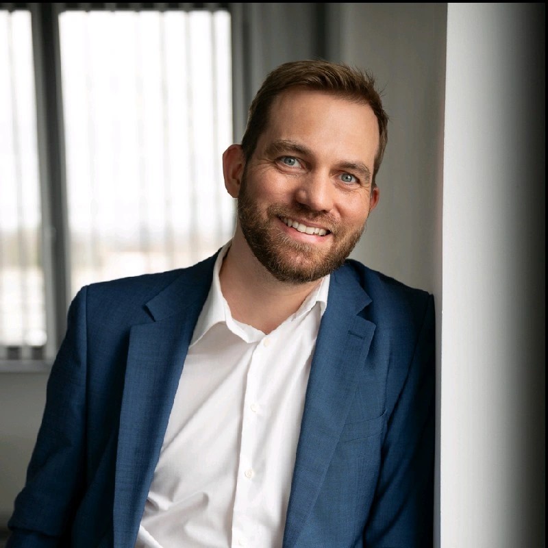 Mann im Anzug lehnt sich an Bürotür an 